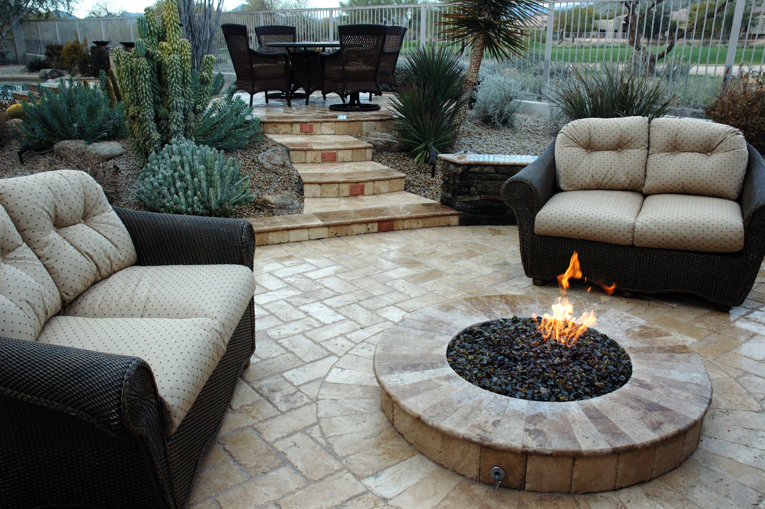 Fire features with adjustable gas valve built out of masonry and travertine with sofas for sitting.