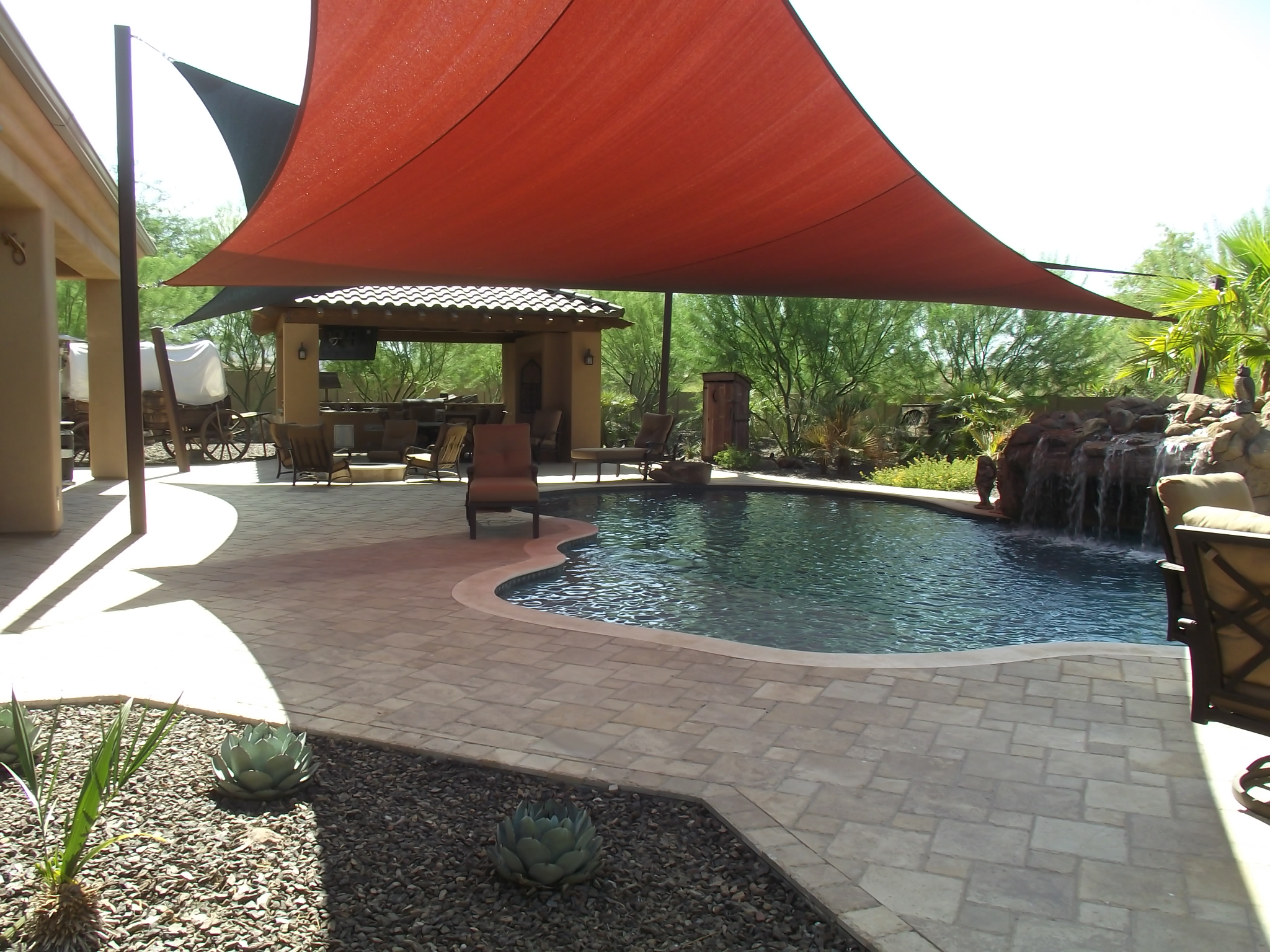 Hardscape and travertine pavers installed in a backyard with a pool.