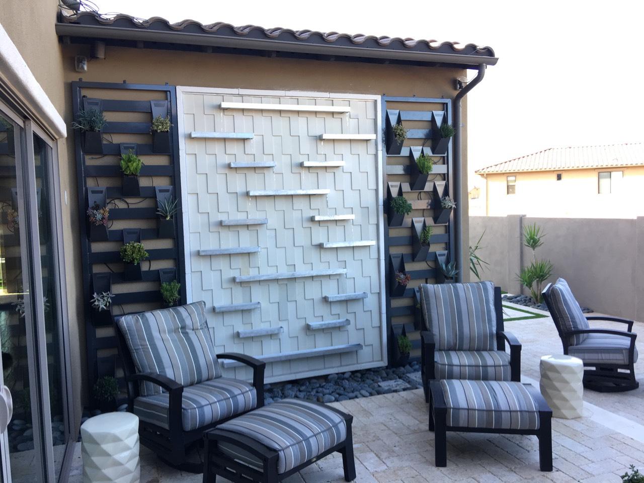 Water feature wall fountain with stacked stone and modern landscaping with sound for ambiance to enjoy outdoor spaces.